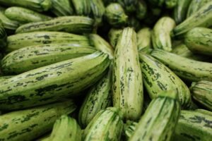 A close-up view of abundant fresh green zucchinis stacked together, showcasing their healthy texture.